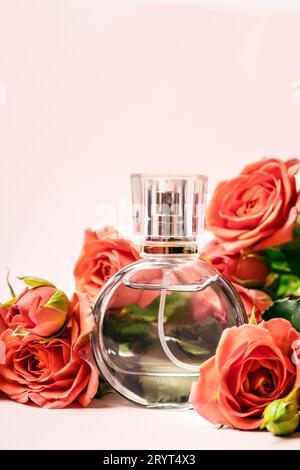 Profumo circondato da rose di corallo su sfondo rosa Foto Stock