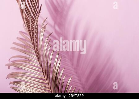 Foglie tropicali dorate dipinte su sfondo rosa pastello. Layout creativo naturale Foto Stock