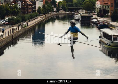 Bydgoszcz, Polonia - agosto 2022 fiume Brda a Bydgoszcz, uomo che attraversa una scultura fluviale , di un uomo che si bilancia su un filo, vecchio edificio granaio, Kuyavian Foto Stock