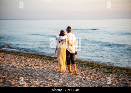 Una coppia attraente che cammina sulla spiaggia, sotto il cielo blu Foto Stock