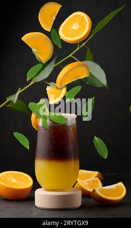 Caffè ghiacciato con succo d'arancia in un bicchiere trasparente, rinfrescante caffè in bumble sul tavolo Foto Stock