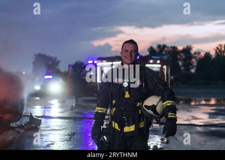 Ritratto di un eroico vigile del fuoco in una tuta protettiva. Vigile del fuoco in operazioni antincendio. Foto Stock