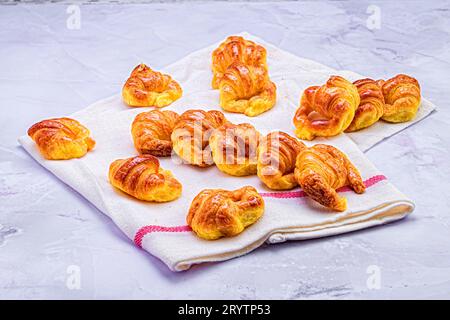 Una gamma di croissant appena sfornati disposti insieme a un tovagliolo bianco piegato Foto Stock