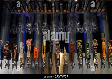 L.A., California, USA - 15 settembre 2023: Una varietà di loghi di birre artigianali sono mostrati in un bar, con bicchieri da birra da mezzo iarda sopra. Foto Stock