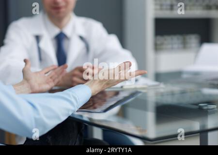 Una foto ravvicinata delle mani di una paziente che sta gestendo vicino ad un medico durante un appuntamento in un ospedale. Foto Stock