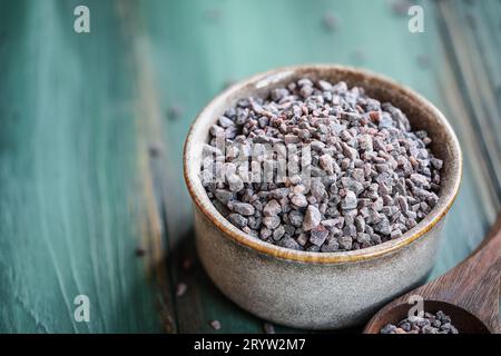 Sale nero indiano kala namak in ciotola blu su sfondo grigio primo piano