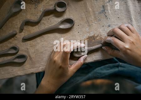 Primo piano di mani che danno forma a un cucchiaio di argilla Foto Stock