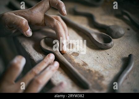 Primo piano di mani che danno forma a un cucchiaio di argilla Foto Stock