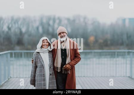 Elegante coppia anziana a piedi vicino al fiume, durante la fredda giornata invernale. Foto Stock