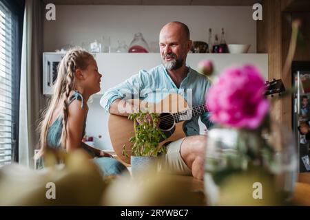 Padre che suona la chitarra per sua figlia carina. Foto Stock