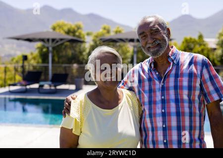 Ritratto di una felice coppia birazziale anziana che abbraccia e sorride in giardino Foto Stock