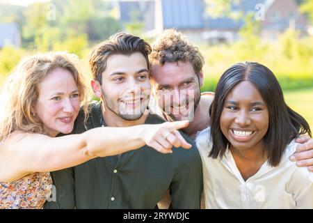 Gruppo di giovani amici o colleghi multietnici che si divertono l'uno con l'altro in un ambiente informale all'aperto dopo il lavoro Foto Stock