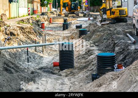 Vista della ricostruzione stradale con un'ampia trincea, tubi idrici e fognari sostituiti e molti pozzetti di ispezione in plastica Foto Stock