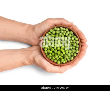 Grani sbucciati di piselli verdi organici in un recipiente in ceramica con mani su sfondo bianco, vista dall'alto. Piselli verdi nei palmi femminili. Proteine vegetali, sane Foto Stock