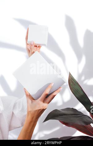 Donna in un accappatoio bianco si prende cura della sua pelle e la idrata il suo viso con un siero Foto Stock