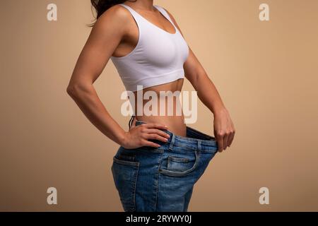 Tagliata di signora in grandi jeans a dimostrazione dei risultati della dieta Foto Stock