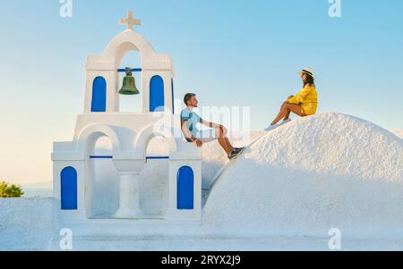 Giovani coppie di turisti visitano Oia Santorini in Grecia durante l'estate con case e chiese imbiancate a calce Foto Stock