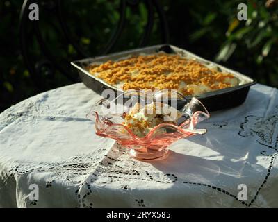 Un primo piano del gelato in un bicchiere con un vassoio di torta su una tovaglia all'aperto Foto Stock