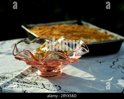 Un primo piano del gelato in un bicchiere con un vassoio di torta su una tovaglia all'aperto Foto Stock