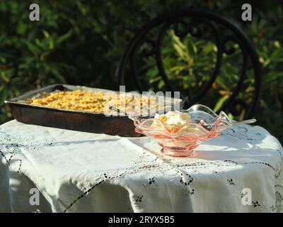 Un primo piano del gelato in un bicchiere con un vassoio di torta su una tovaglia all'aperto Foto Stock