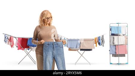 Donna che tiene un paio di jeans davanti ai vestiti su scaffali isolati su sfondo bianco Foto Stock