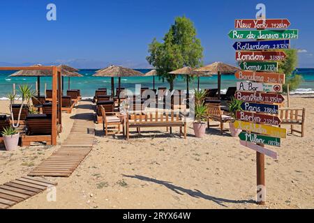 Indicazioni per destinazioni esotiche in un bar sulla spiaggia, Agistri Island, Golfo Saronico, Grecia. Maggio 2023. Foto Stock