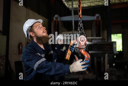 Due tecnici che ispezionano e testano il funzionamento delle gru di sollevamento in impianti industriali pesanti. Foto Stock