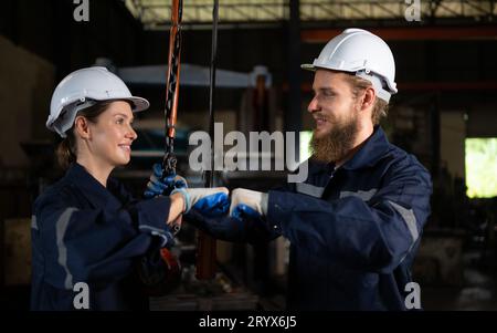 Due tecnici che ispezionano e testano il funzionamento delle gru di sollevamento in impianti industriali pesanti. Foto Stock