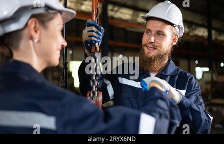 Due tecnici che ispezionano e testano il funzionamento delle gru di sollevamento in impianti industriali pesanti. Foto Stock