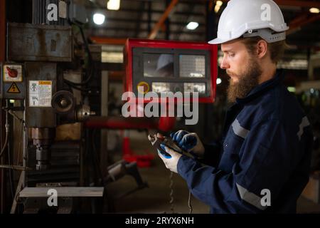 Un ritratto degli ingegneri meccanici sta verificando le condizioni di funzionamento di una vecchia macchina che è stata utilizzata per un certo periodo di tempo. In un fac Foto Stock