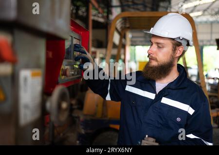 Un ritratto degli ingegneri meccanici sta verificando le condizioni di funzionamento di una vecchia macchina che è stata utilizzata per un certo periodo di tempo. In un fac Foto Stock