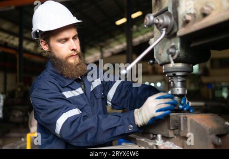 Un ritratto degli ingegneri meccanici sta verificando le condizioni di funzionamento di una vecchia macchina che è stata utilizzata per un certo periodo di tempo. In un fac Foto Stock