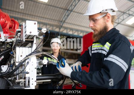 Ingegnere elettrico con la missione di installare un sistema elettrico del braccio robotizzato Foto Stock