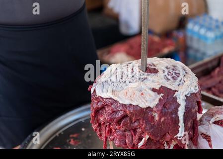 Il maestro sta preparando il kebab turco per cucinare con carne rossa, carne di kebab doner cruda, gyros greci sullo spiedo in un ristorante. Foto di alta qualità Foto Stock