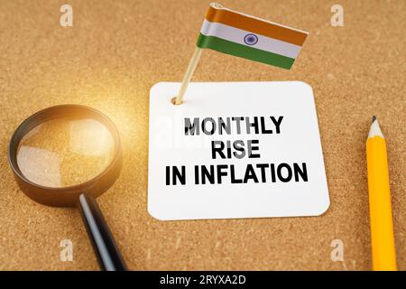 Economia e finanza. Sul tavolo ci sono una lente d'ingrandimento, una matita, la bandiera dell'India e un foglio di carta con l'iscrizione - aumento mensile Foto Stock