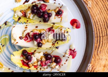 Antipasto vegetariano a base di barche di indivia belga fresche ripiene di pinoli tostati, formaggio bleu, frutti di bosco freschi e olio d'oliva fresco Foto Stock