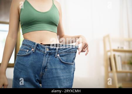 Donna asiatica dietetica perdita di peso. Donna magra in jeansÂ oversize Foto Stock