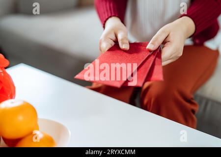 Donna asiatica che dà busta rossa per le celebrazioni del Capodanno lunare. Tenere la mano nella confezione rossa Foto Stock