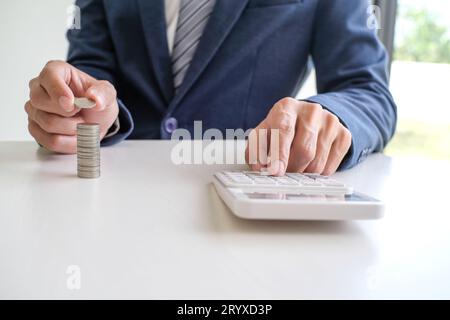 Risparmio di denaro. Imprenditore contabile verifica la crescita delle attività e risparmia denaro impilando le monete con la calcolatrice. Contabilità Foto Stock