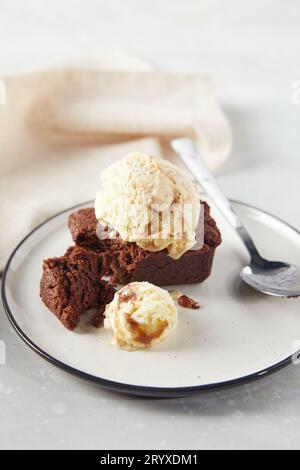 Dessert al cioccolato brownie con cucchiaio di gelato cremoso alla nocciola sul piatto con tovagliolo Foto Stock