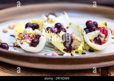 Antipasto vegetariano a base di barche di indivia belga fresche ripiene di pinoli tostati, formaggio bleu, frutti di bosco freschi e olio d'oliva fresco Foto Stock