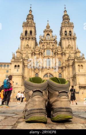 Questi stivali sono stati fatti per camminare. Un pellegrino ha lasciato le sue scarpe vecchie e usurate di fronte alla famosa cattedrale di Santiago de Compostela, meta di tutti i pellegrini sulla via di San James o Camino de Santiago. Foto Stock