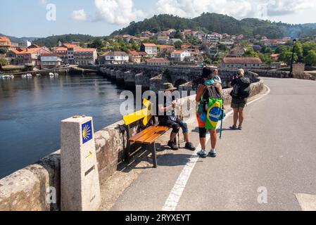 Pellegrini al ponte medievale Pontesampaio che attraversa il fiume Verdugo nei pressi di Arcade. Un primo ponte fu costruito lì dai Romani, il ponte esistente con i suoi dieci archi fu costruito durante il Medioevo e ristrutturato nel corso del XVII e XIX secolo. Foto Stock