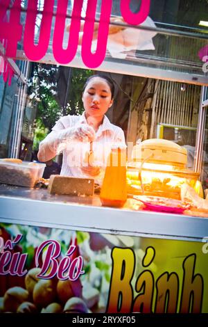 Una ragazza serve Banh My Que per strada ad Hanoi, Vietnam, Asia Foto Stock