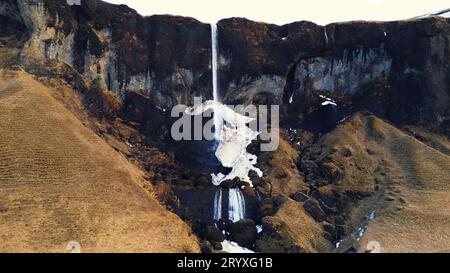 Foto con drone di foss, una cascata di sidu in islanda che cade dalla scogliera creando una splendida vista panoramica e un percorso panoramico. Fantastica cascata nordica con ruscello che scorre lungo le colline islandesi. Rallentatore. Foto Stock