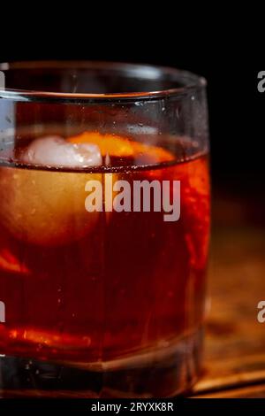 Cocktail alcolico Negroni o cocktail analcolico, bevanda con ghiaccio e scorza d'arancia come decorazione su tavolo di legno Foto Stock