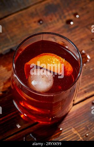 Cocktail alcolico Negroni o cocktail analcolico, bevanda con ghiaccio e scorza d'arancia come decorazione su tavolo di legno Foto Stock