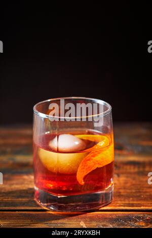 Cocktail alcolico Negroni o cocktail analcolico, bevanda con ghiaccio e scorza d'arancia come decorazione su tavolo di legno Foto Stock