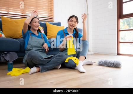 Due giovani donne in uniforme che puliscono la stanza mentre sono sedute a terra Foto Stock