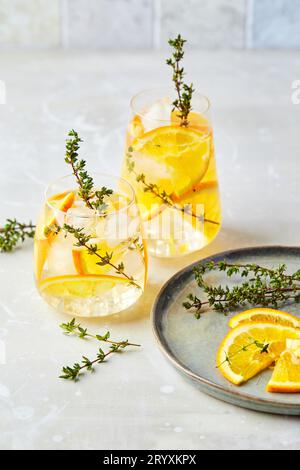 Cocktail rinfrescante con ghiaccio, arancia e timo. Rinfrescante cocktail o mocktail estivo fatto in casa, alcolici o analcolici, o D Foto Stock